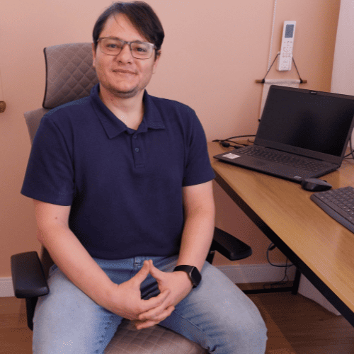 O psicólogo Fabiano sorrindo em frente ao notebook, representando o acolhimento e a segurança das consultas de psicologia online.